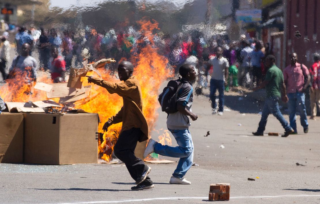 Protesters set up a burning barricade as they clash with police in Harare in August.