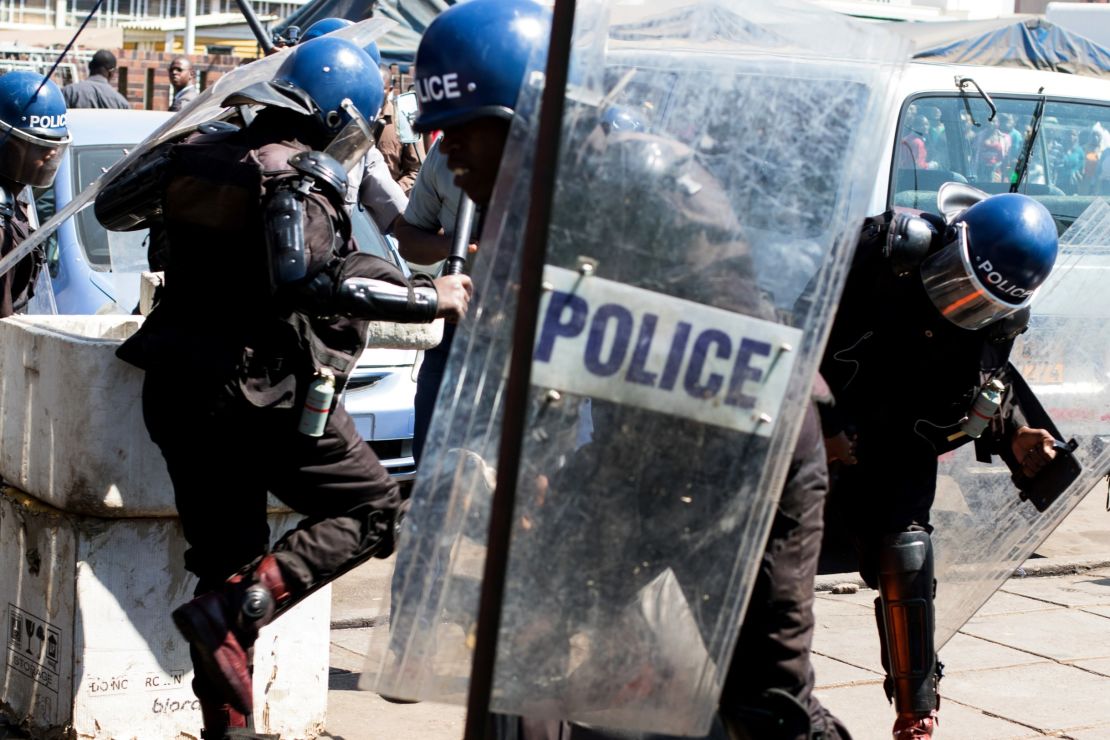 Anti-riot policemen surround an activist at Harare Central Police Station in August.