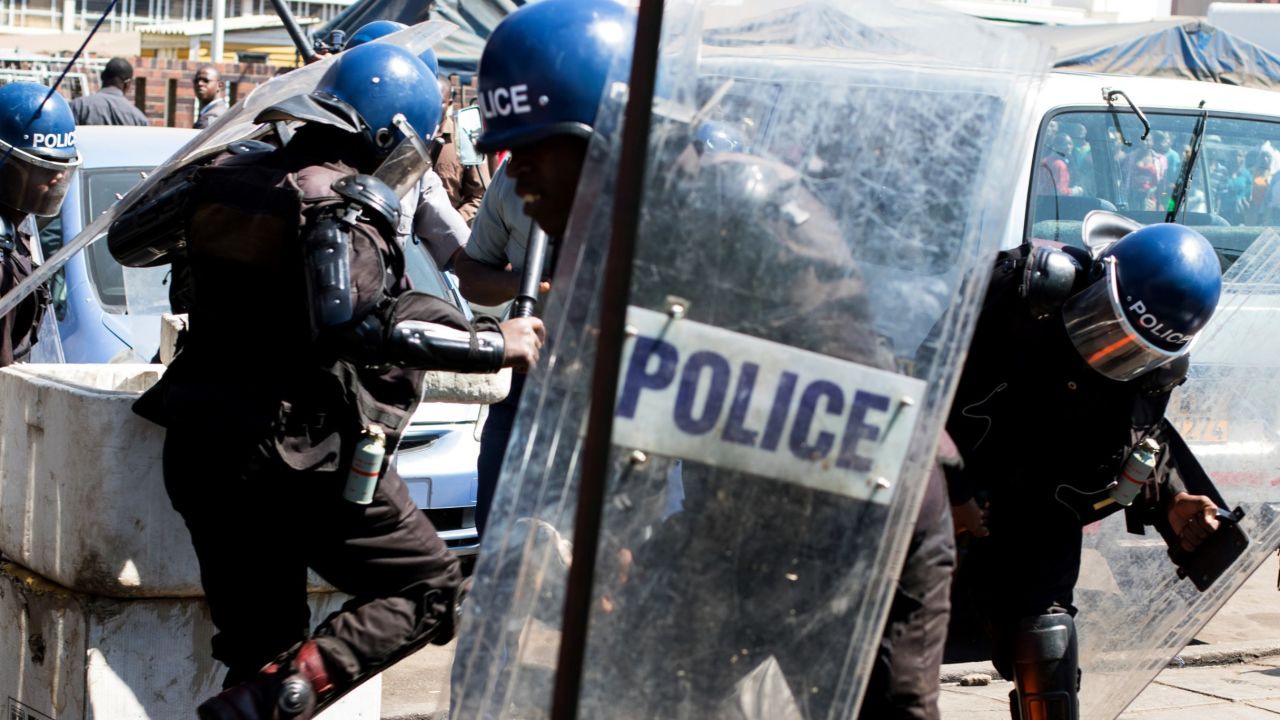 Anti-riot policemen surround an activist at Harare Central Police Station in August.
