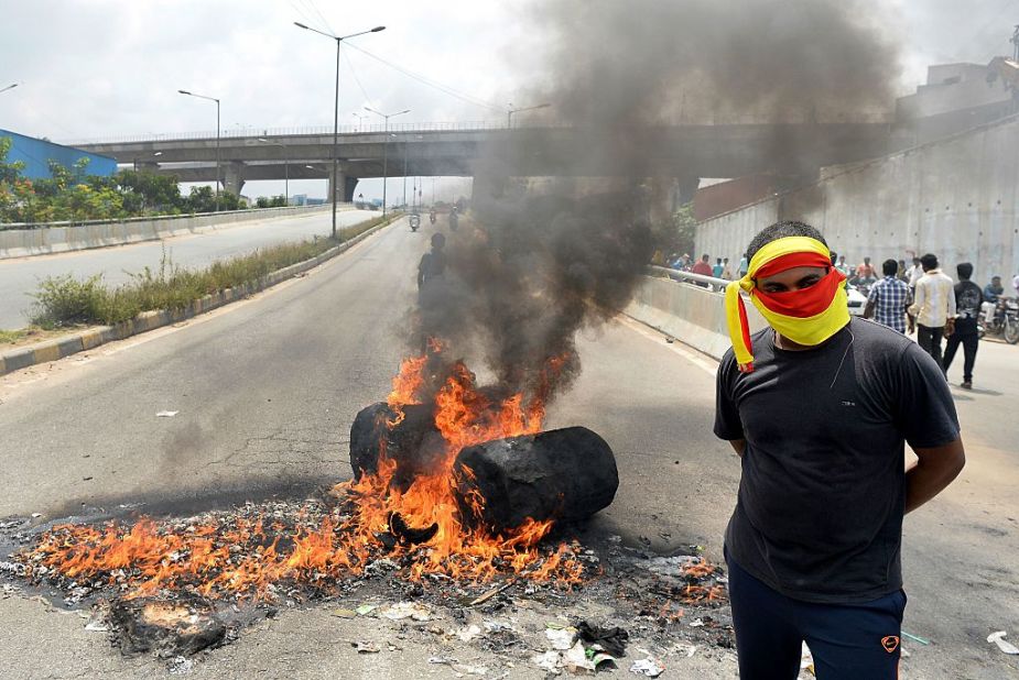 An Indian activist stands beside a traffic blockade at a major connecting road during a statewide strike over water in Bangalore on September 9, 2016.