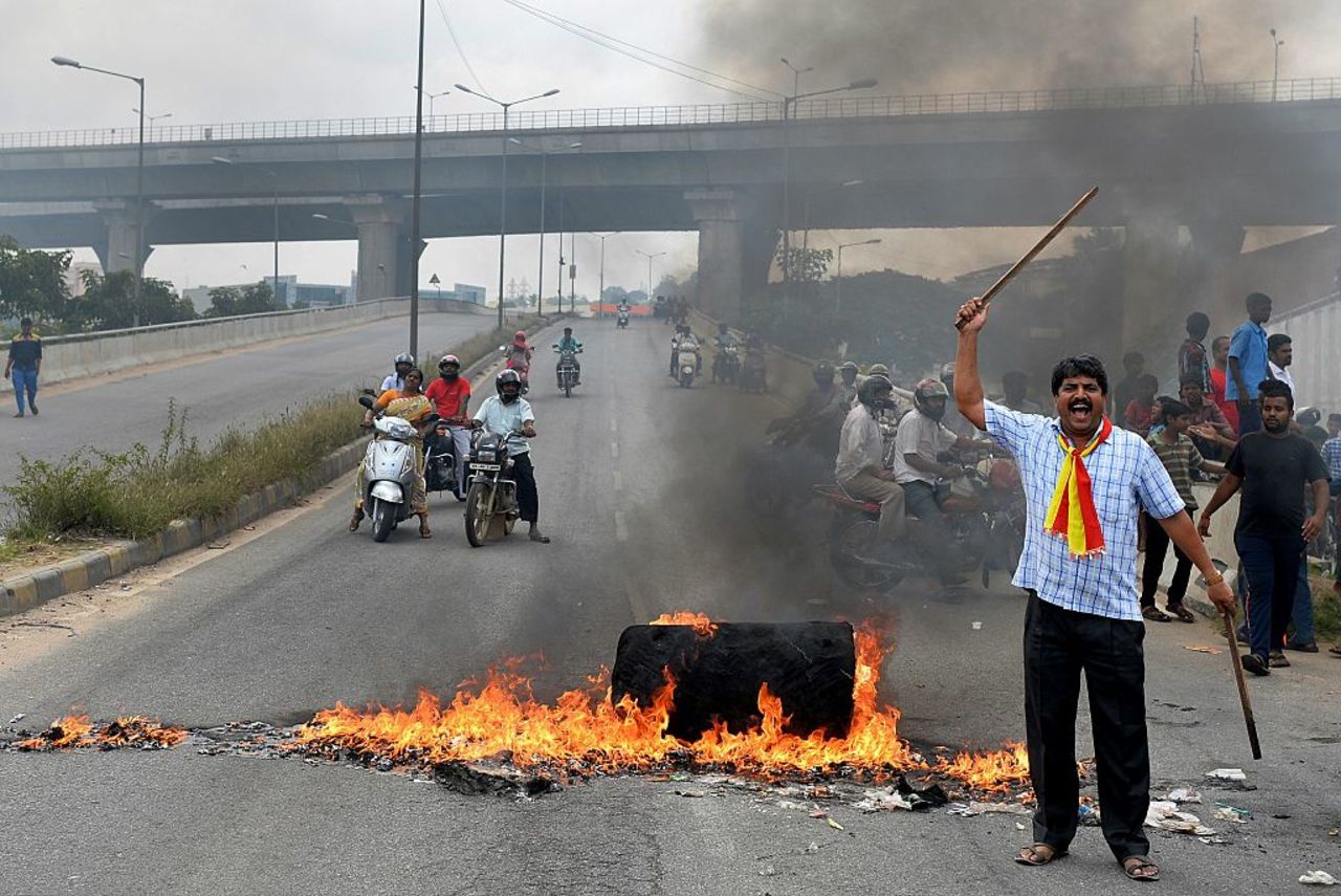 An activist stands beside a traffic blockade at a major connecting road during a statewide strike in Bangalore.