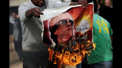 A man holds a burning poster of Moammar Gadhafi in Benghazi in March 2011.