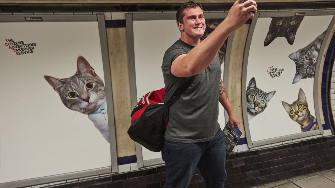 Amused commuter takes quick selfie in front of posters