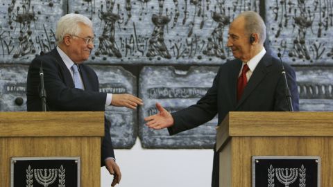 Palestinian President Mahmoud Abbas reaches to shake hands with Israeli President Shimon Peres prior to their meeting in Jerusalem on July 22, 2008. Abbas had threatened to withdraw his forces from West Bank cities unless Israel's military halted its raids into the areas.