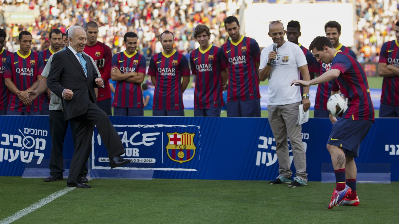 Israeli President Shimon Peres kicks the ball to FC Barcelona's striker Lionel Messi during a soccer clinic in Broomfield Stadium in Tel Aviv on August 4, 2013.