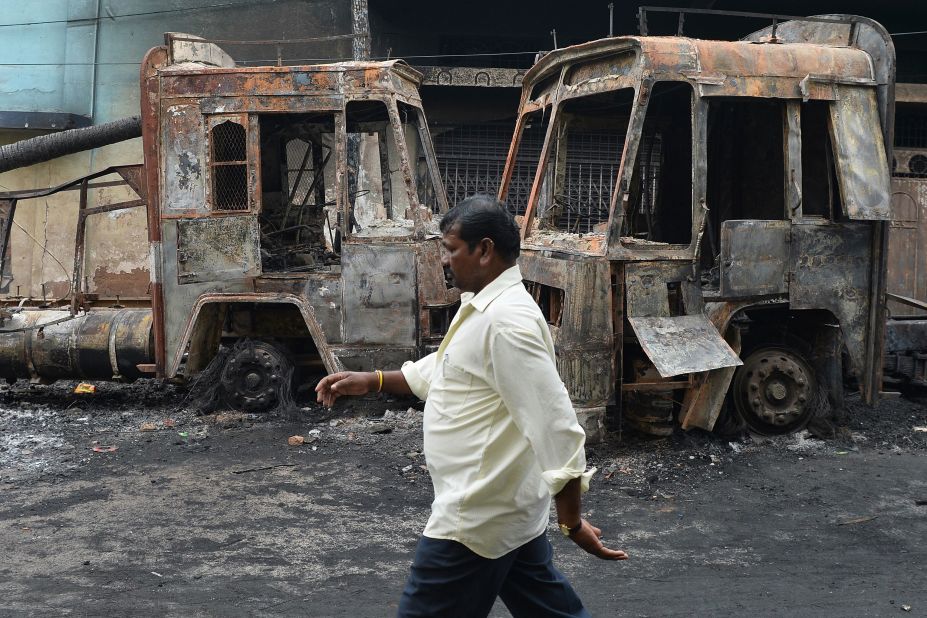 A pedestrian walks past the skeletal remains of a Karnataka state transport bus, September 13, following the clashes during the Cauvery water dispute in Bangalore.