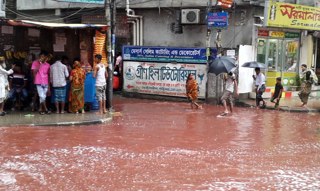 People wade past a road turned red after blood from sacrificial animals on Eid al-Adha mixed with water from heavy rainfall in Dhaka, Bangladesh. 