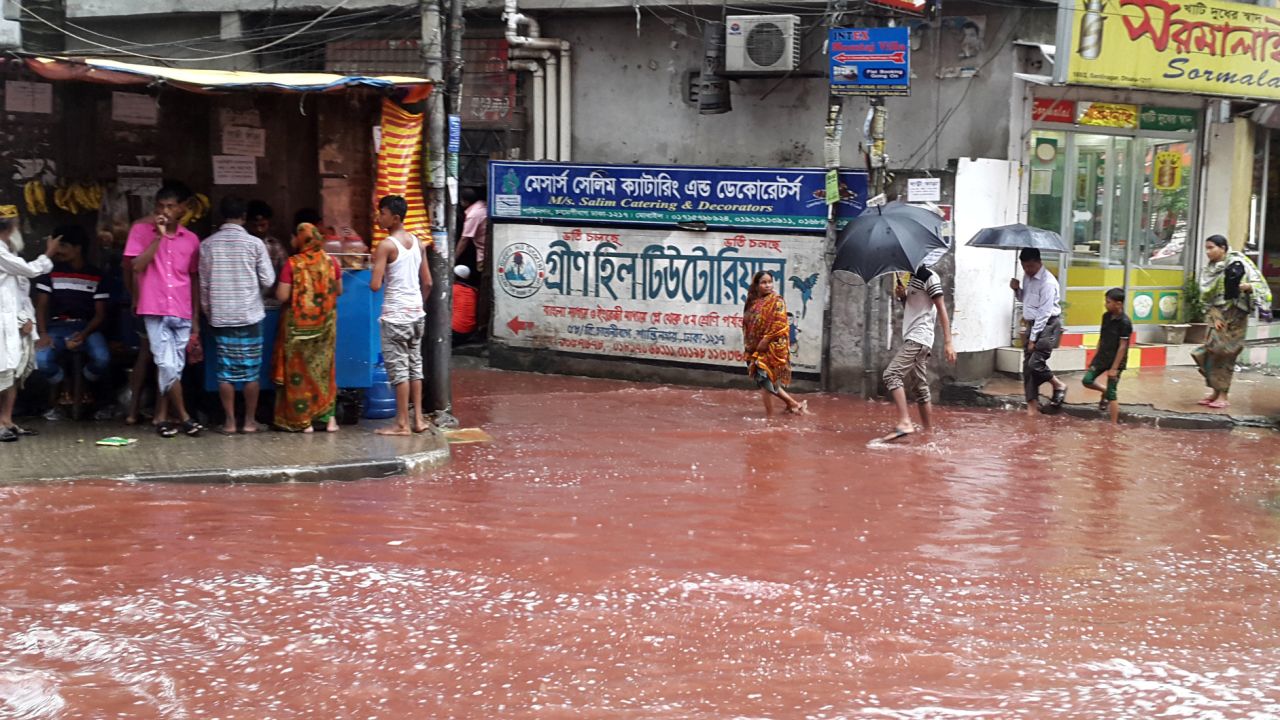 People wade past a road turned red after blood from sacrificial animals on Eid al-Adha mixed with water from heavy rainfall in Dhaka, Bangladesh.