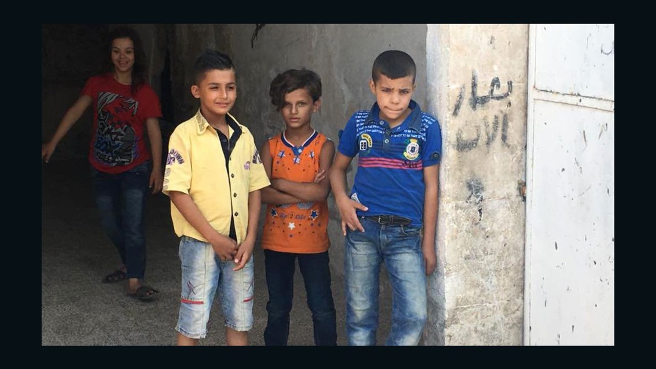 Children appear at an entrance of a destroyed building in Aleppo.
