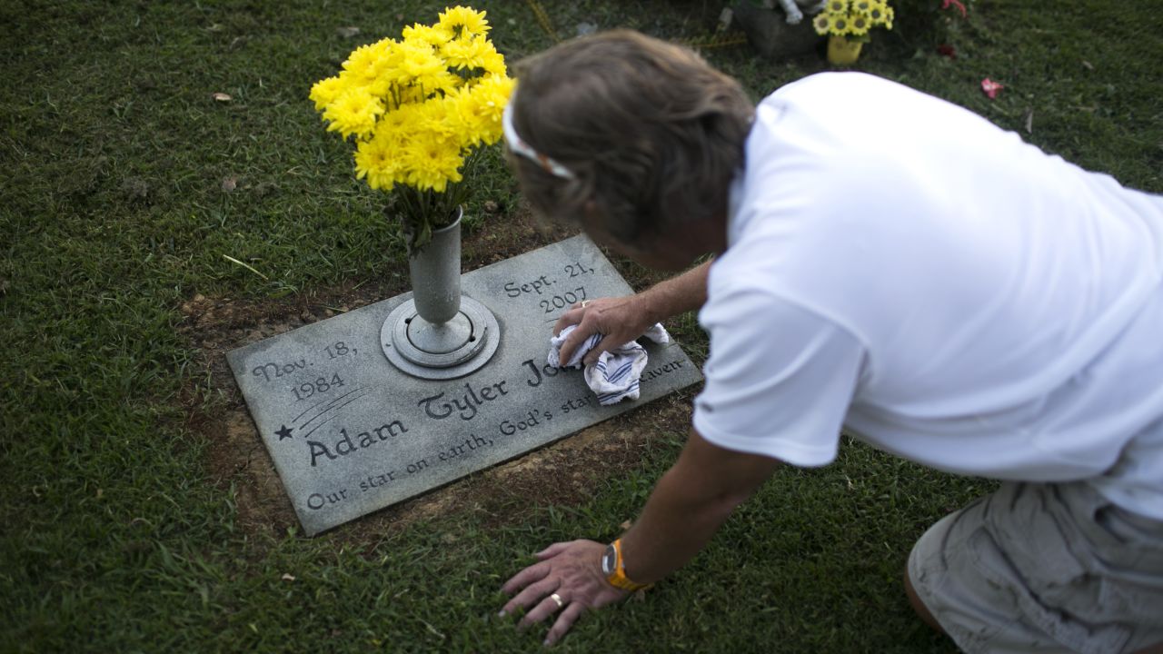 Teddy Johnson polishes the grave of his son, Adam, who died of a heroin overdose in 2007.