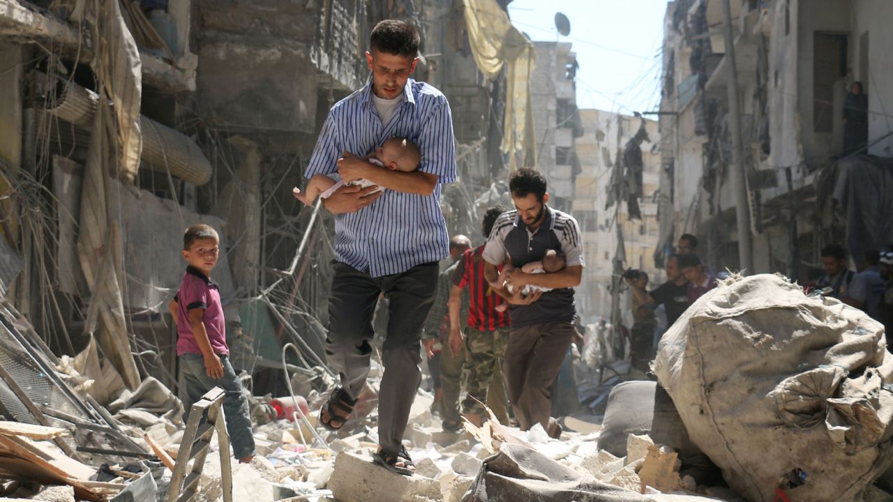 TOPSHOT - Syrian men carrying babies make their way through the rubble of destroyed buildings following a reported air strike on the rebel-held Salihin neighbourhood of the northern city of Aleppo, on September 11, 2016.
Air strikes have killed dozens in rebel-held parts of Syria as the opposition considers whether to join a US-Russia truce deal due to take effect on September 12. / AFP / AMEER ALHALBI        (Photo credit should read AMEER ALHALBI/AFP/Getty Images)