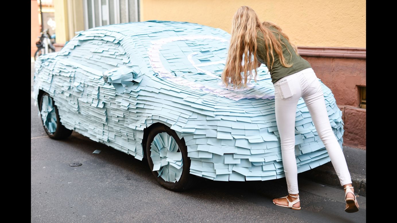 A woman sticks notes on an illegally parked car in Heidelberg, Germany, on Friday, September 9.