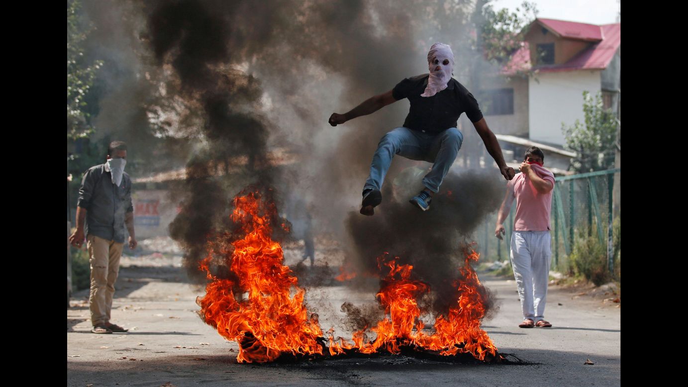 A man jumps over burning debris -- during a protest against recent Kashmir killings -- in Srinagar, India, on Monday, September 12.