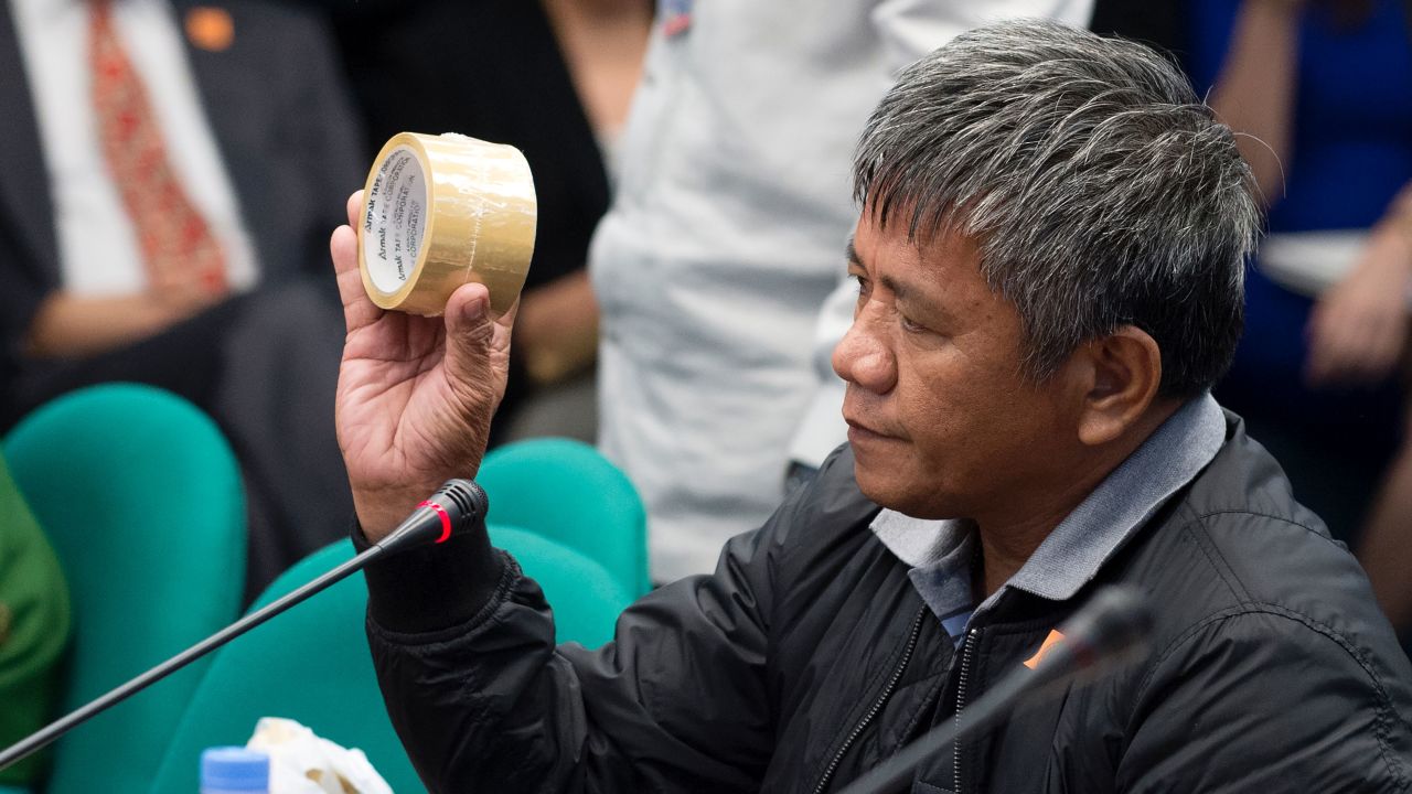 Edgar Matobato holds roll of a packing tape as he testifies during a senate hearing in Manila on September 15, 2016. He said it was used to mask victims' identities.