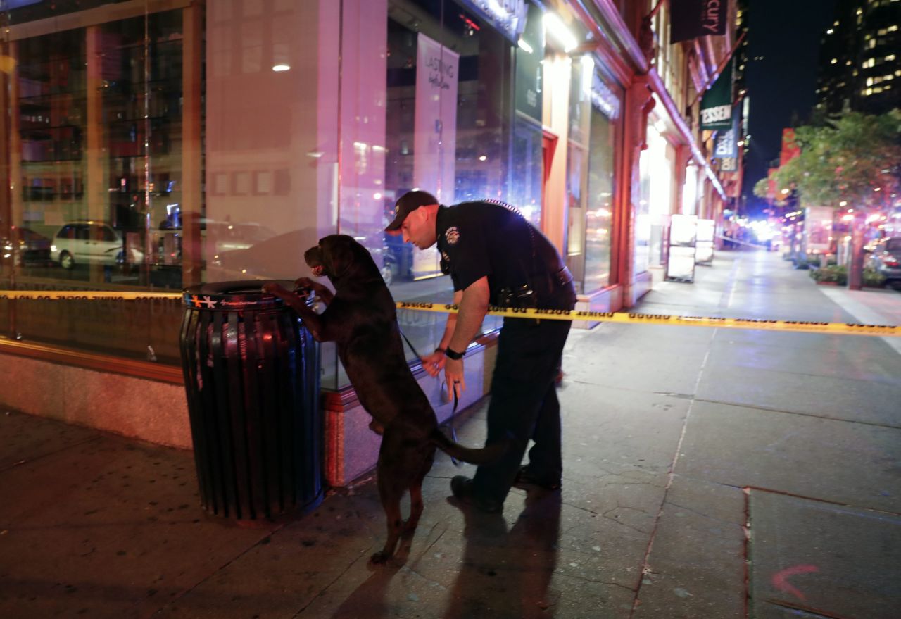 A New York police officer and his dog check a garbage can close to the scene of the explosion.