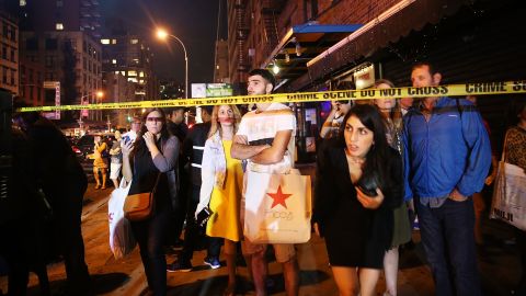 People stand behind police lines as emergency workers and police gather at the scene of the explosion.