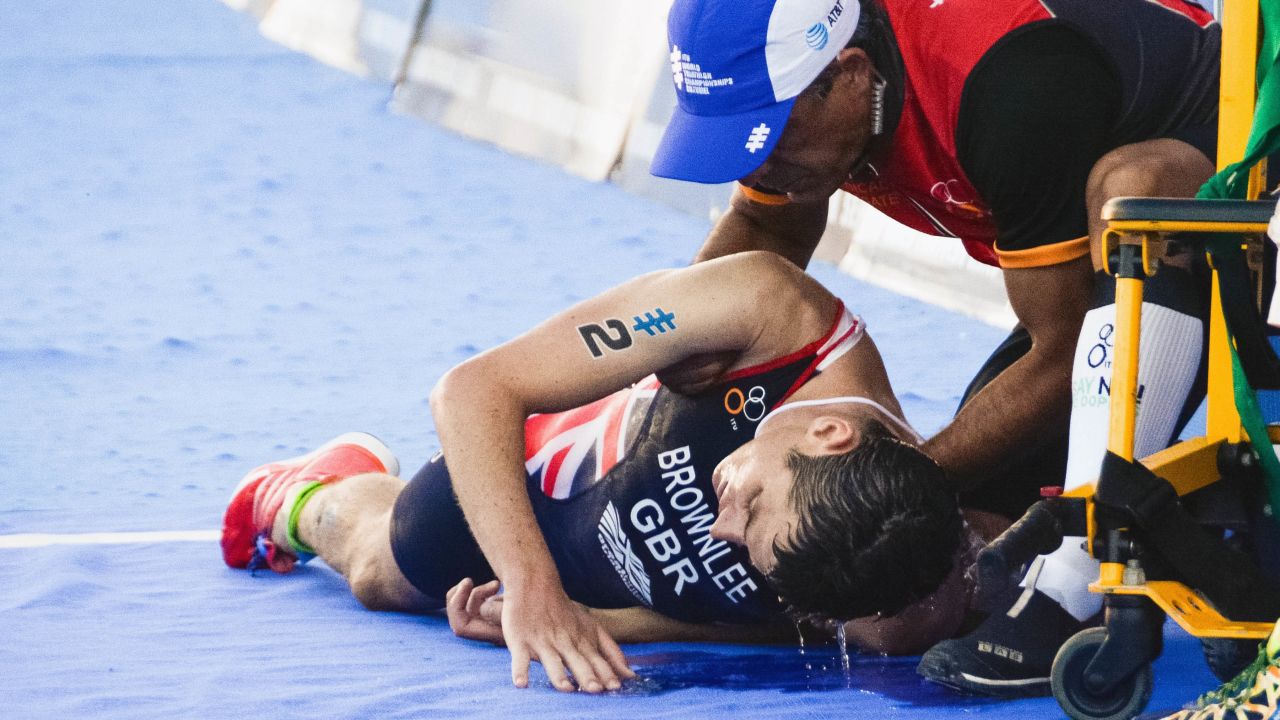 Jonny Brownlee (L) is helped after crossing the line in second place during the 2016 ITU World Triathlon Championships.