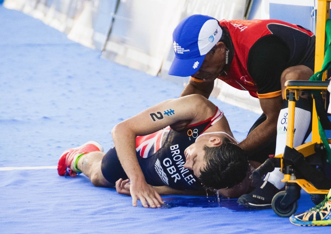 Jonny Brownlee (L) is helped after crossing the line in second place during the 2016  ITU World Triathlon Championships.