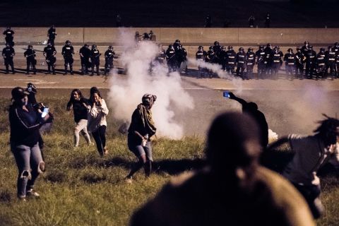 Protesters run from a gas canister after blocking traffic on I-85.