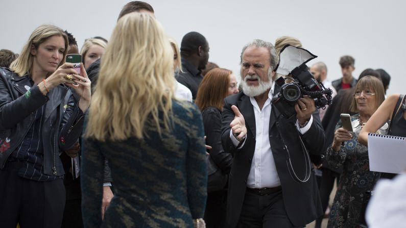 Celebrity photographer Dave Bennett poses a front row guest before the Topshop Unique catwalk show on September 18, 2016.