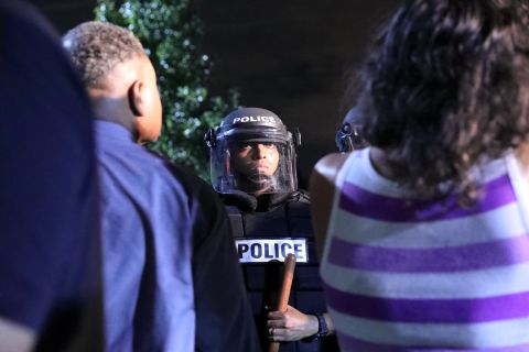A police officer faces protesters.