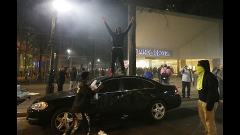 A protester stands on a car roof.