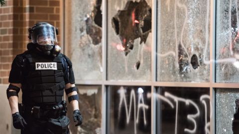 A police officer in riot gear stands near a damaged storefront on September 21.