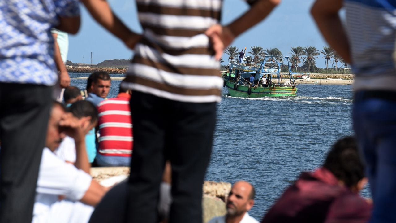 Egyptian men sit along the shore in the Egyptian port city of Rosetta on September 22, 2016 as they watch a boat departing for a search operation.