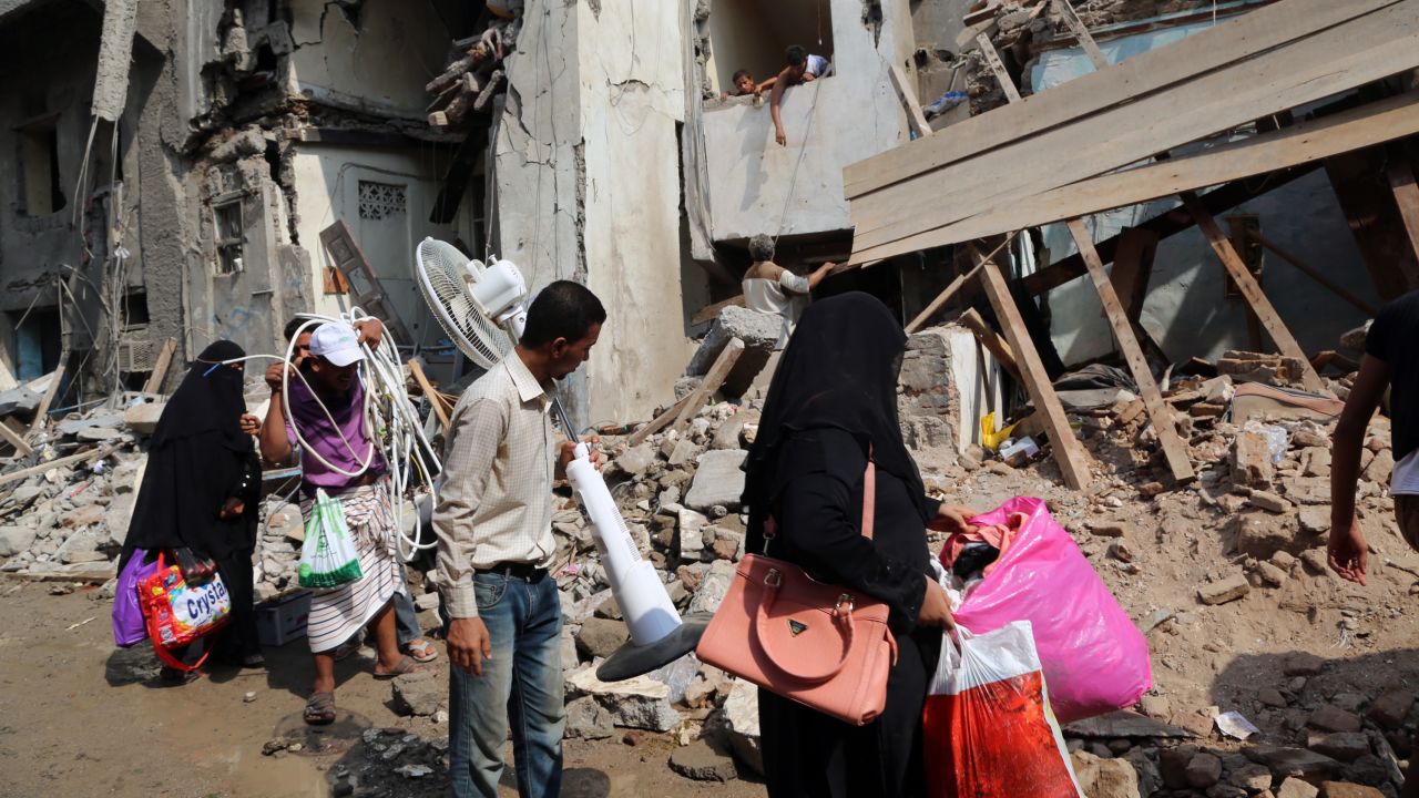 Yemenis carry belongings they recovered from the rubble of buildings destroyed during Saudi-led air strikes in 2016