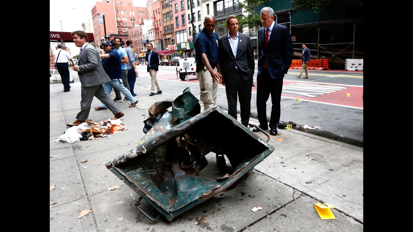 New York Mayor Bill de Blasio, right, and New York Gov. Andrew Cuomo, second right, look over the mangled remains of a dumpster Sunday, September 18, in New York's Chelsea neighborhood. An explosion <a href="http://www.cnn.com/2016/09/17/us/gallery/ny-explosion-0917/index.html" target="_blank">injured 29 people there</a> the night before.