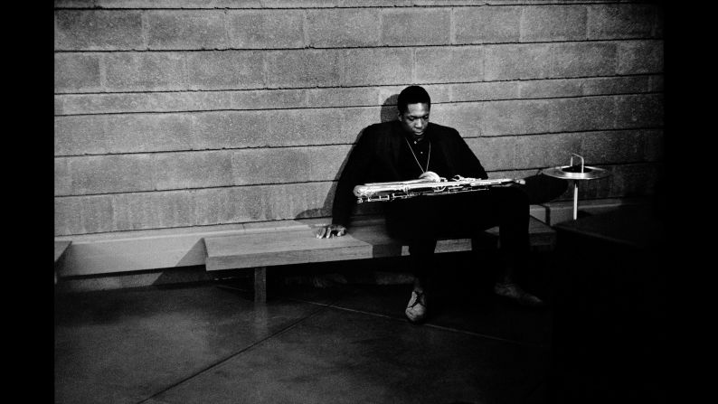 Saxophonist John Coltrane slumps on a bench backstage.