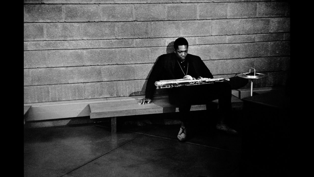 Saxophonist John Coltrane slumps on a bench backstage.