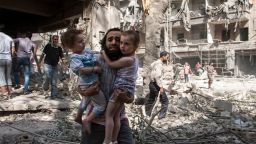 A Syrian man carries his two girls as he walks across the rubble following a barrel bomb attack on the rebel-held neighbourhood of al-Kalasa in the northern Syrian city of Aleppo on September 17, 2015. Once Syria's economic powerhouse, Aleppo has been ravaged by fighting since the rebels seized the east of the city in 2012, confining government forces to the west. AFP PHOTO / KARAM AL-MASRI / AFP / KARAM AL-MASRI AND -        (Photo credit should read KARAM AL-MASRI/AFP/Getty Images)