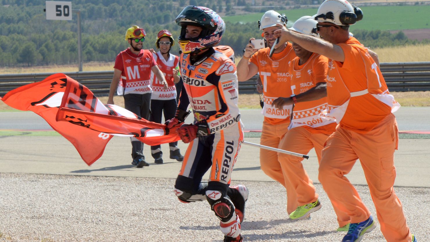 Marc Marquez celebrates his Aragon MotGP win with marshals at the Motorland track in Alcaniz.