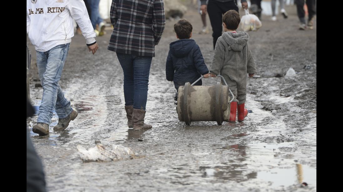 Two young boys walk in the mud inside "The Jungle" in December 2015.