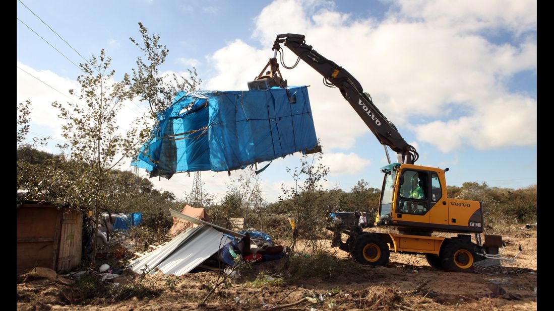 A digger lifts a migrant's makeshift tent during a destruction operation in September 2009.