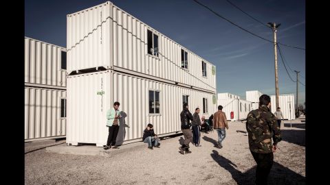 Migrants walk past housing containers in "The Jungle" on Tuesday, February 16.