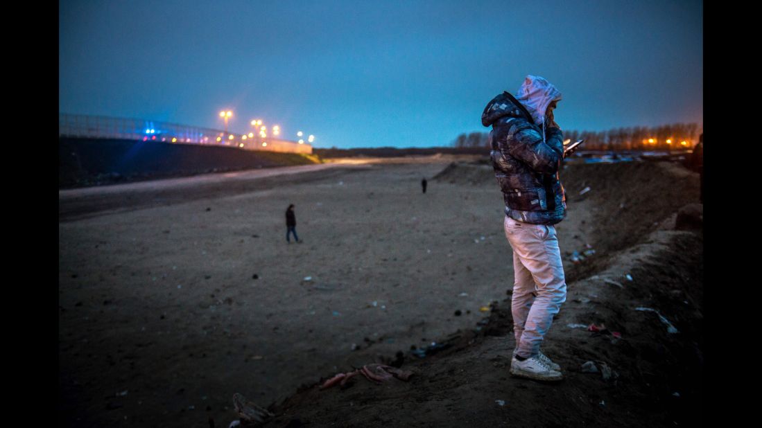 A migrant makes a phone call near "The Jungle" on March 1.