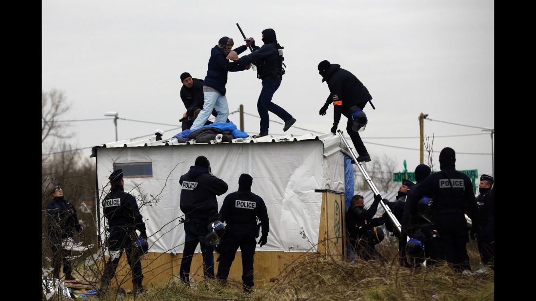 A woman fights with a police officer as she is removed from the top of a hut on March 1. Police and demolition teams were starting to dismantle makeshift shelters and relocating people to accommodations nearby.