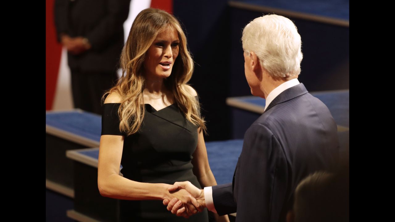 Trump's wife, Melania, shakes hands with Clinton's husband, former U.S. President Bill Clinton.