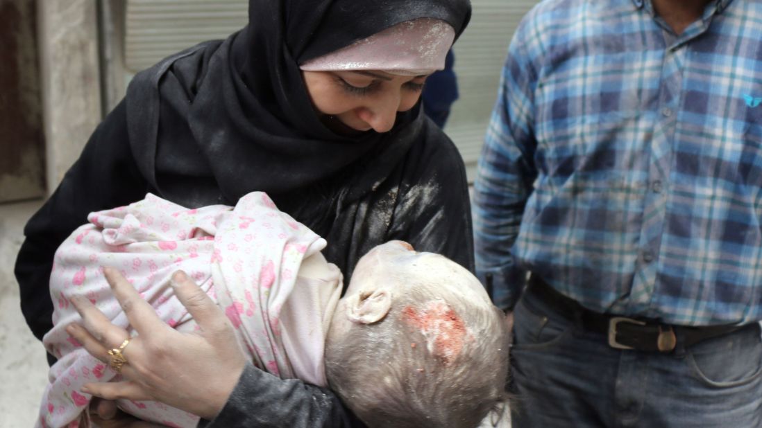 A Syrian woman carries the body of her infant after he was recovered. 