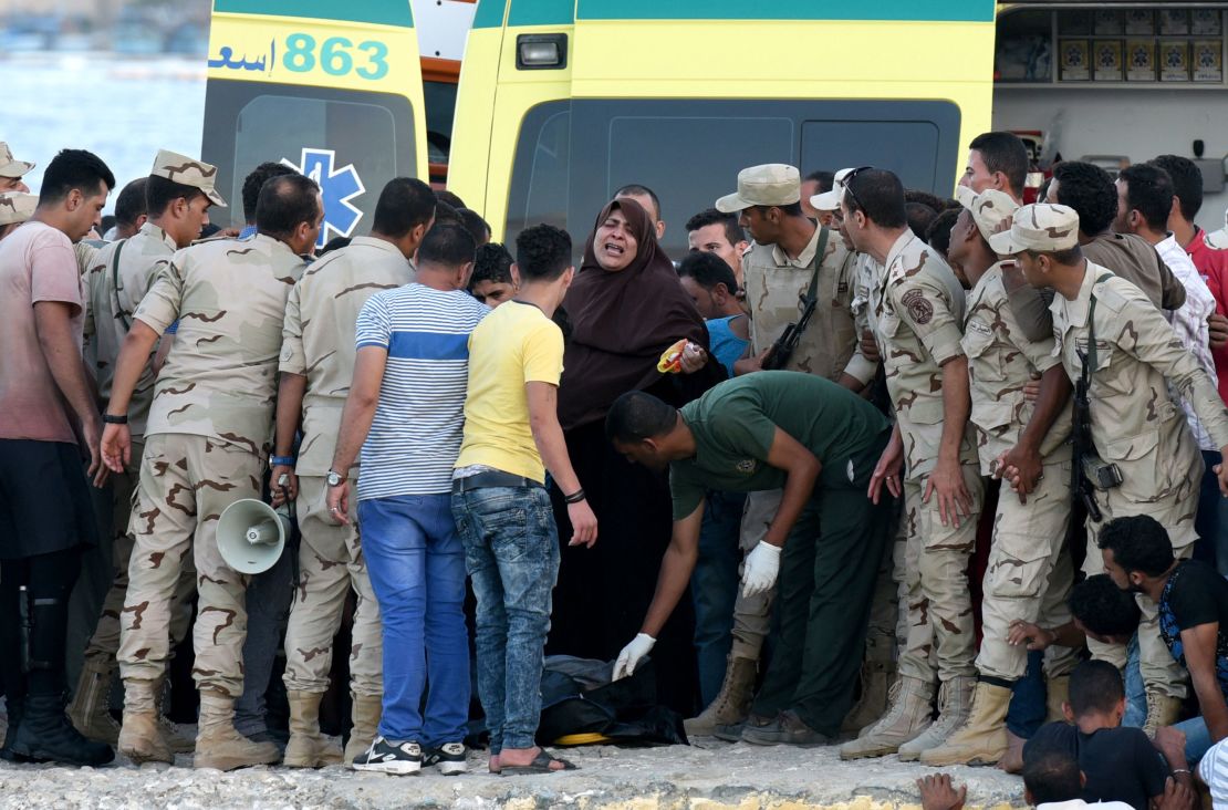 Egyptian policemen and medics stand over a body of a migrant