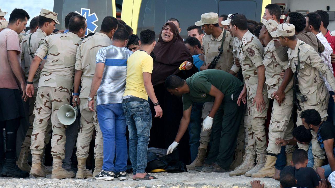 Egyptian policemen and medics stand over a body of a migrant