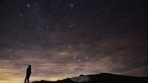 A photographer looks at the sky at night in northern Italy during the 2015 Geminid meteor shower.
