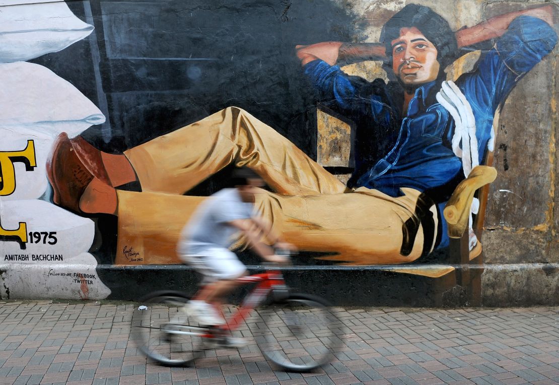 An Indian cyclist rides past a mural of Bollywood actor Amitabh Bachchan from his classic film "Deewar" on the eve of Bachchan's 70th birthday in Mumbai on October 10, 2012.