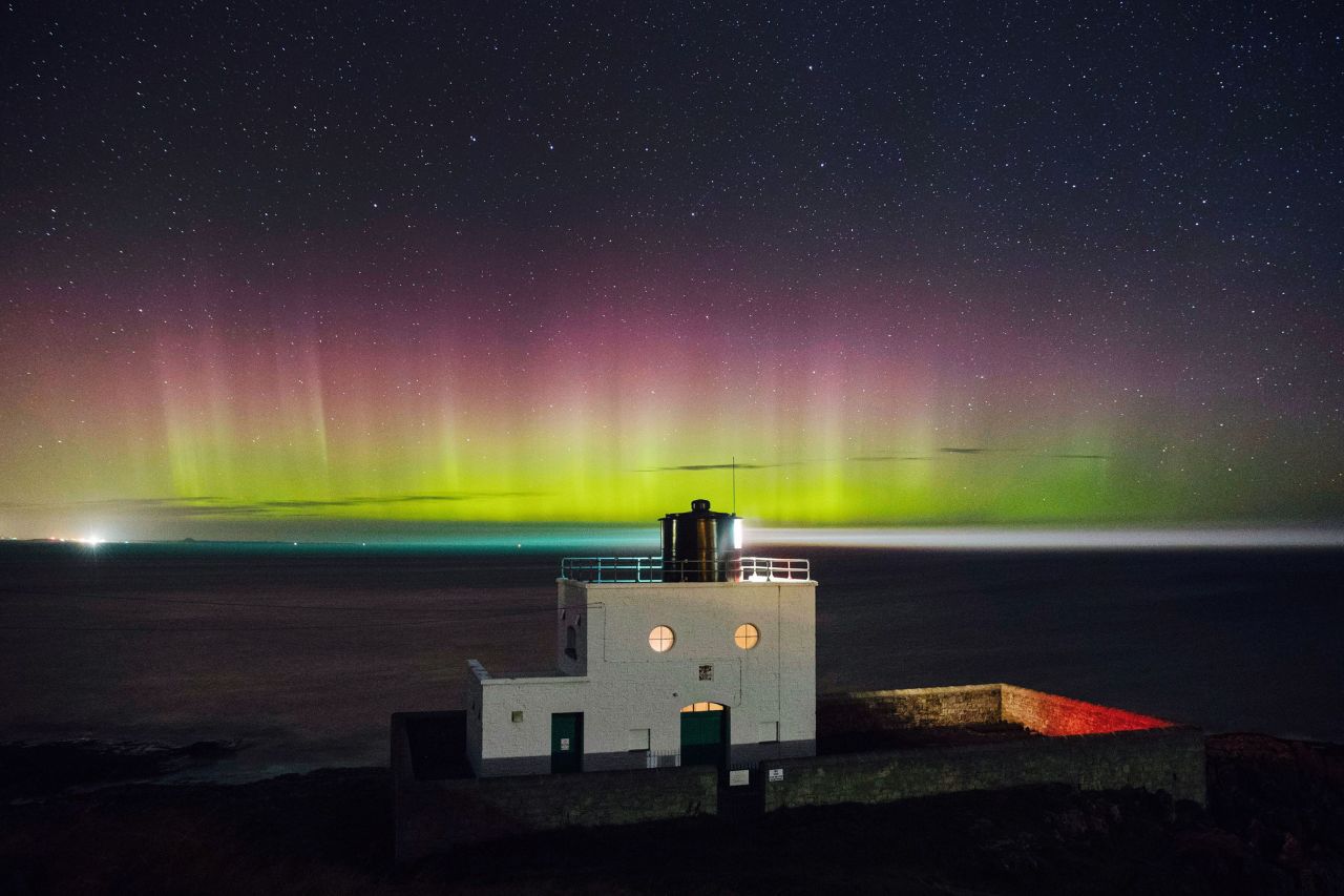 The Northern Lights, or Aurora Borealis appear in the sky over Bamburgh lighthouse at stag Rock in Northumberland.