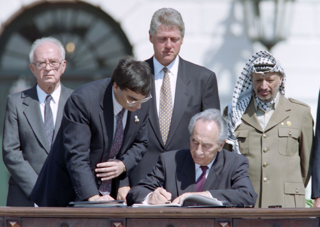 Shimon Peres signs the Oslo Accords at the White House as Yitzhak Rabin,  President Bill Clinton and Yasser Arafat look on.