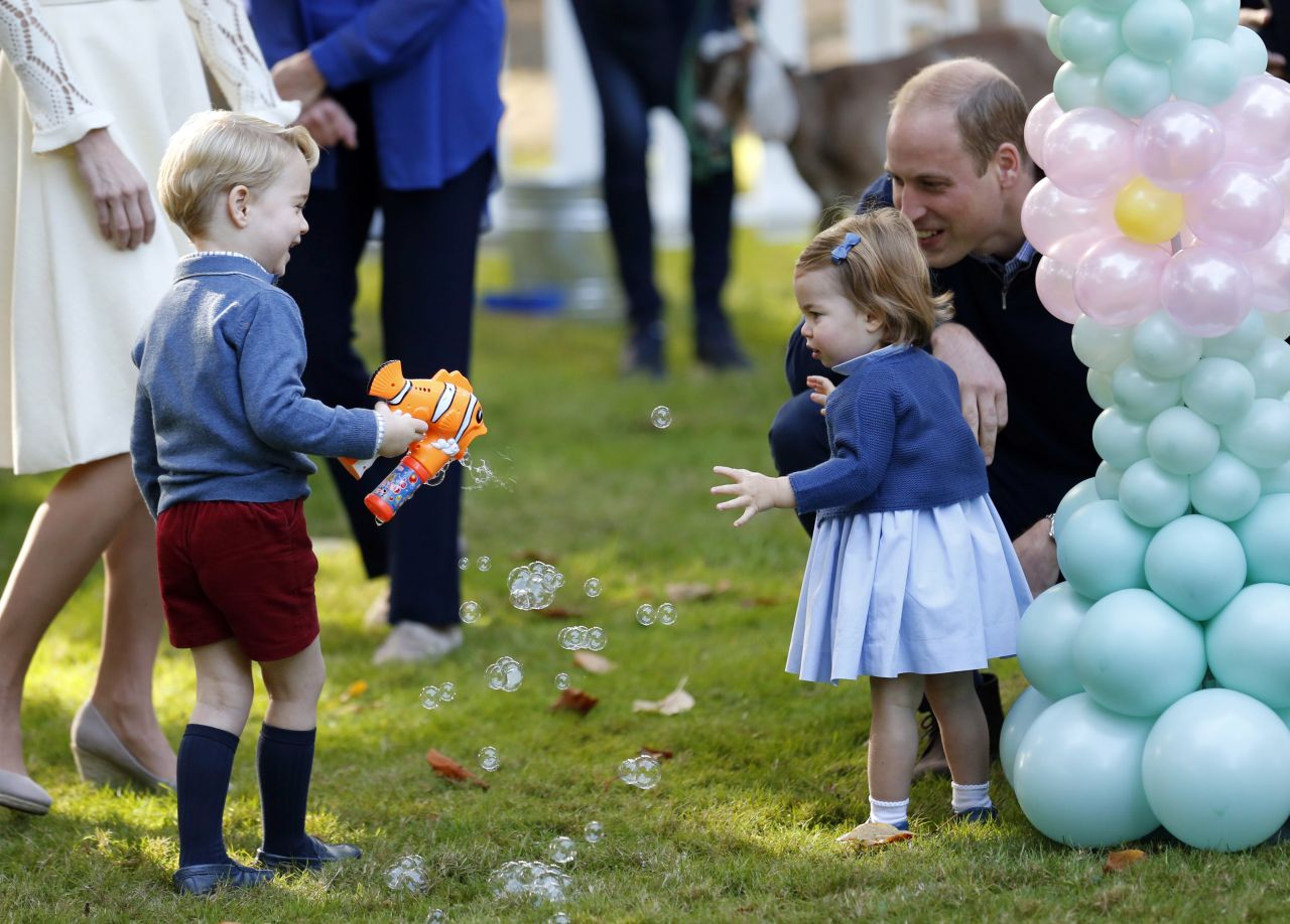 Prince George plays with a bubble gun near his sister, Princess Charlotte, and his dad, Prince William, on September 29. 