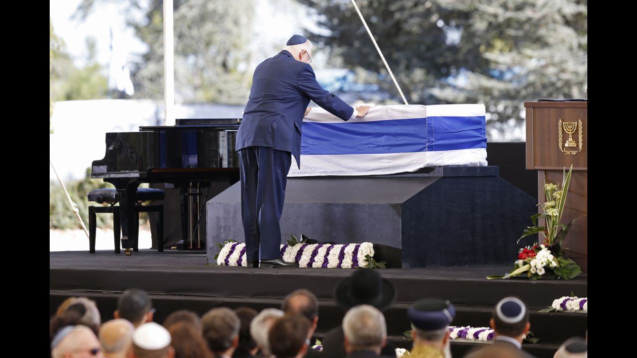 Israeli President Reuven Rivlin touches Peres' coffin. In his tribute, Rivlin said that Peres was "the man of whom we thought time could never stop."