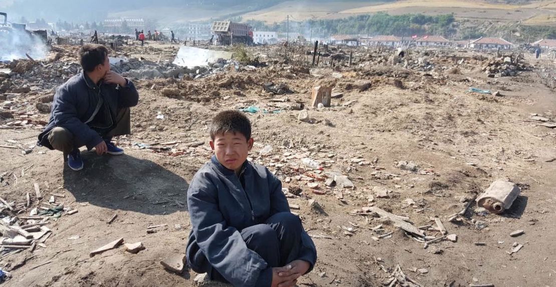 A young North Korean boy sits amid a flood-ravaged landscape in Hamgyong province.